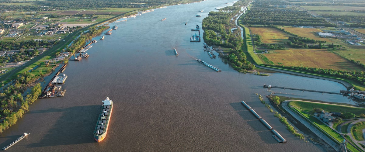 A river with ships, a bridge, and surrounding farmland.