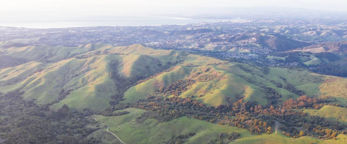 Evening sunlight shines on the green hills of the East Bay in Northern California. This open area, east of San Francisco Bay, is green in the winter due to rain and golden during the summer.