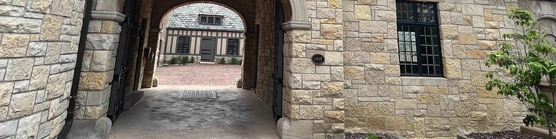 A Tudor-style building with stone walls, a wooden-framed window, and a brick roof.