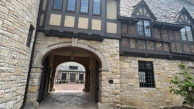 Um edifício em estilo Tudor com paredes de pedra, janelas de madeira e telhado de tijolos.