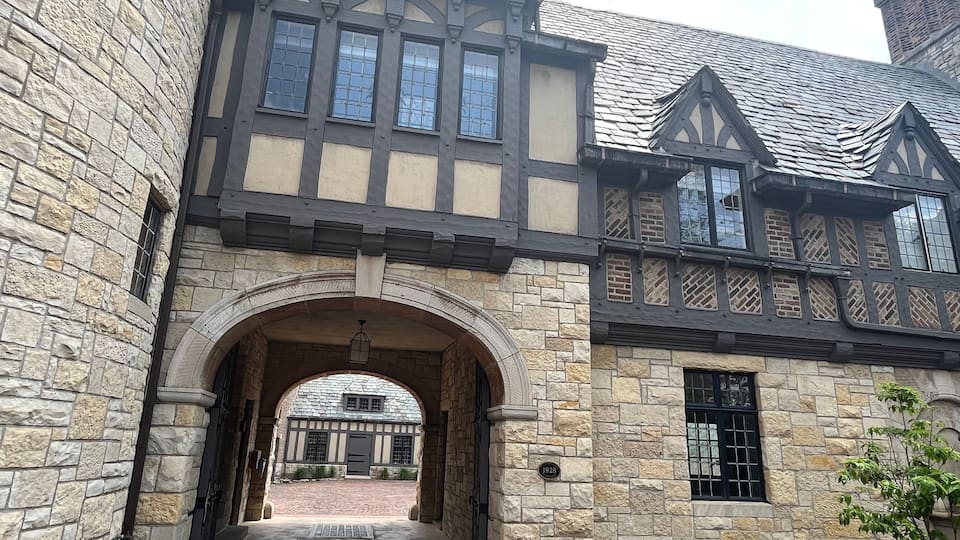 A Tudor-style building with stone walls, a wooden-framed window, and a brick roof.
