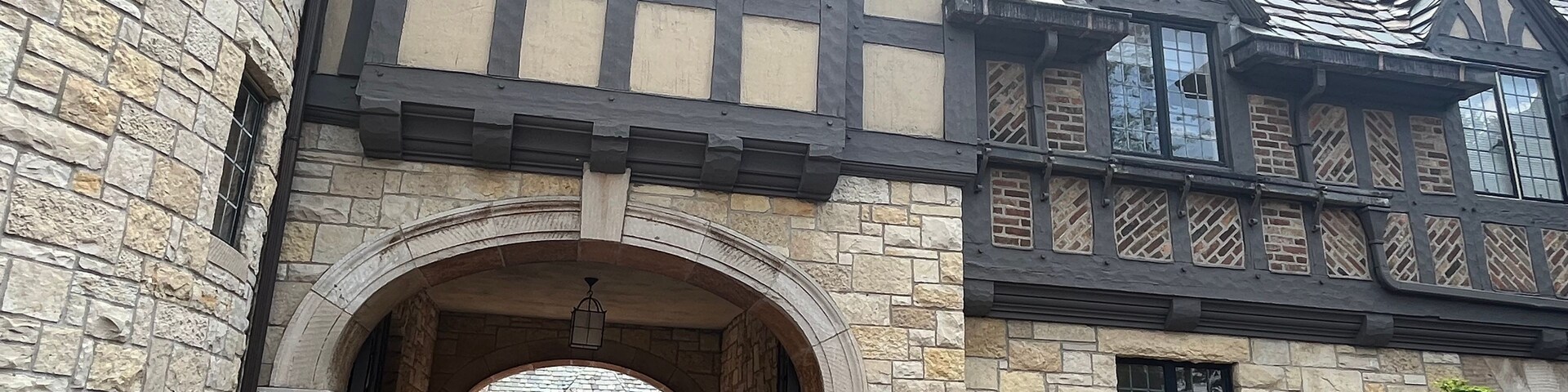 Un edificio in stile Tudor con muri in pietra, una finestra con stipite in legno e un tetto in mattoni.