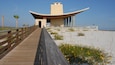 A wooden boardwalk leading to a modern building with a curved roof and columns.