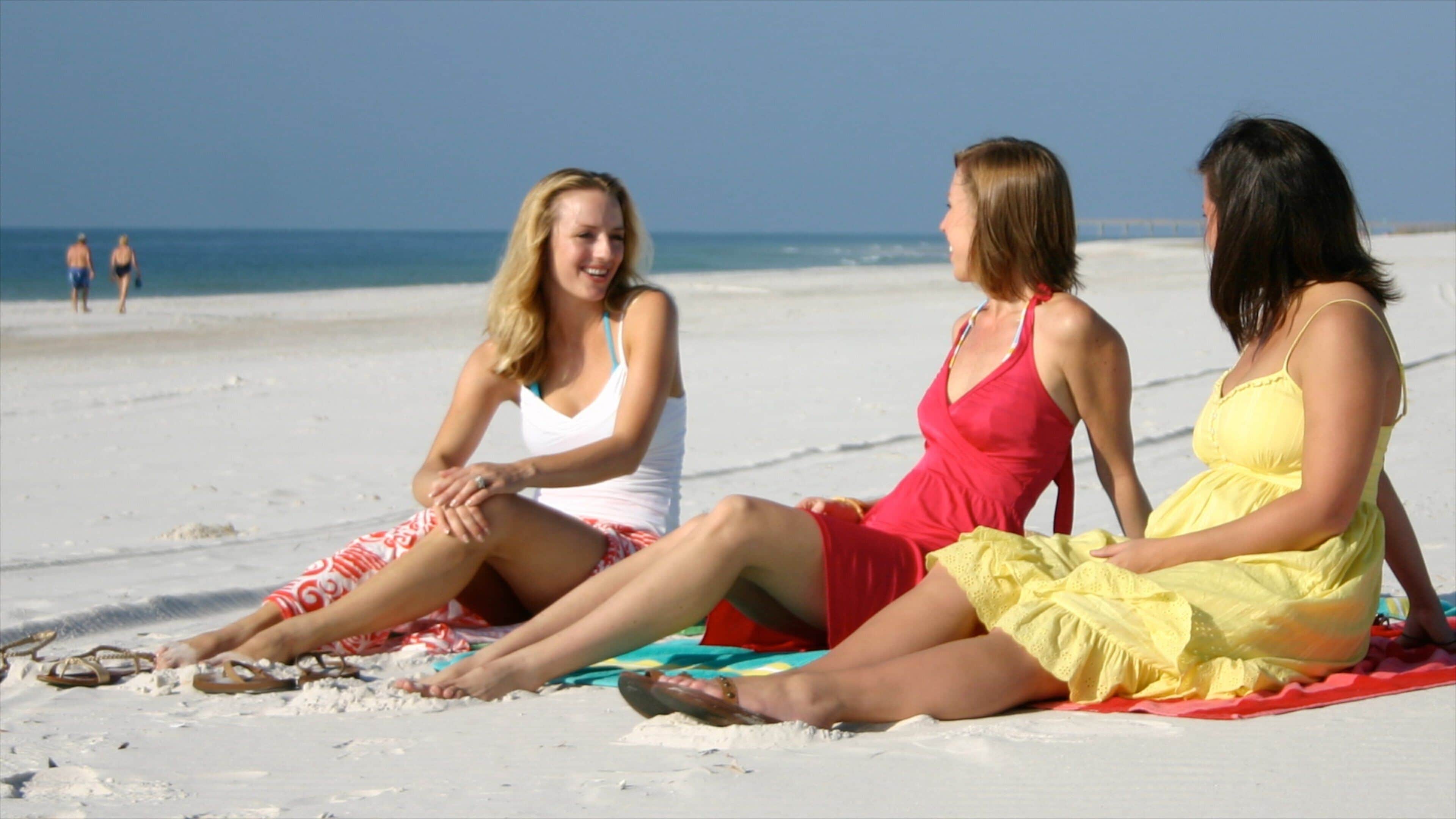 Orange Beach fasiliteter samt sandstrand og tropisk landskap i tillegg til en liten gruppe med mennesker