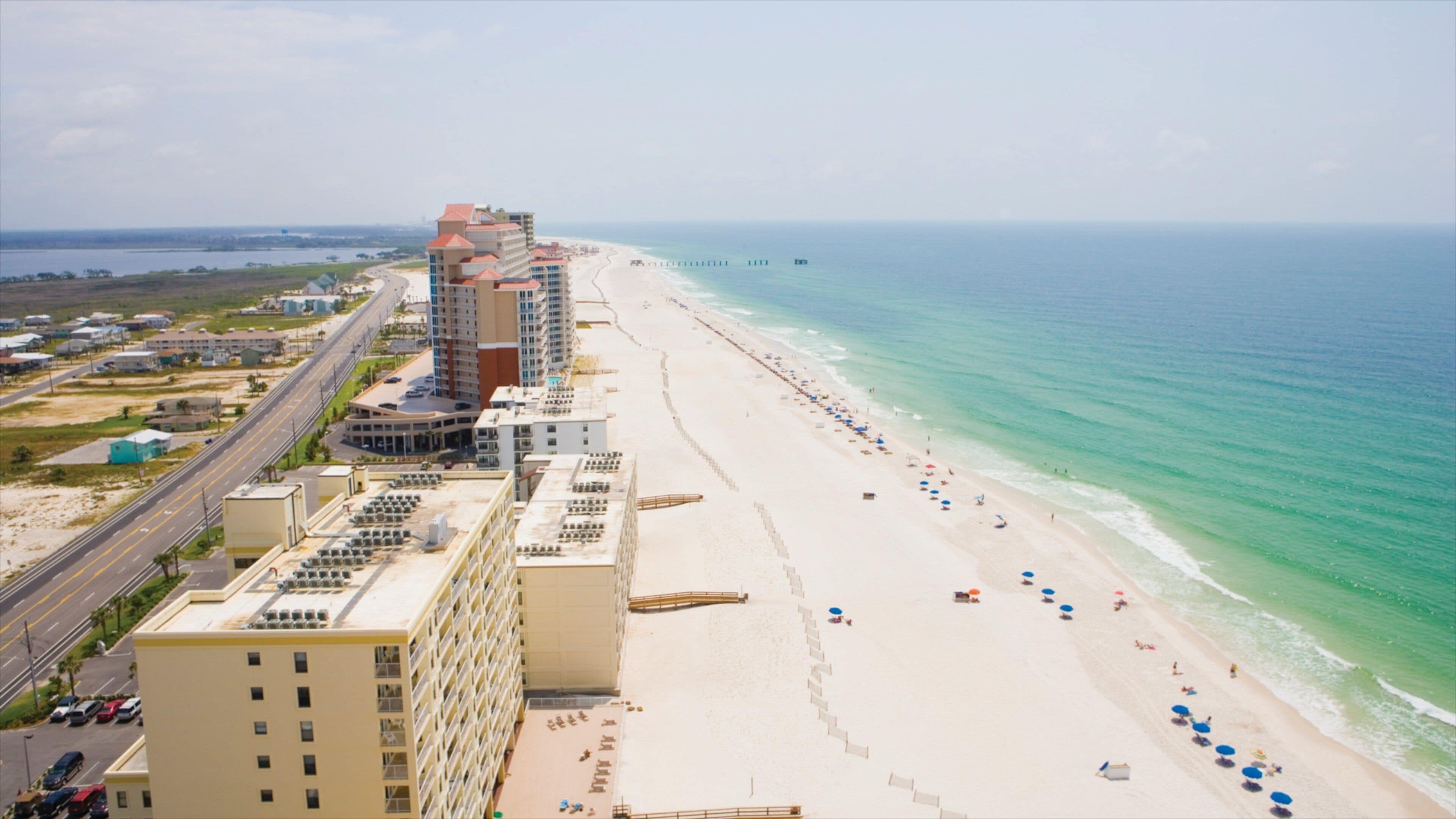 A coastal cityscape with a wide beach, high-rise buildings, and a clear view of the ocean.