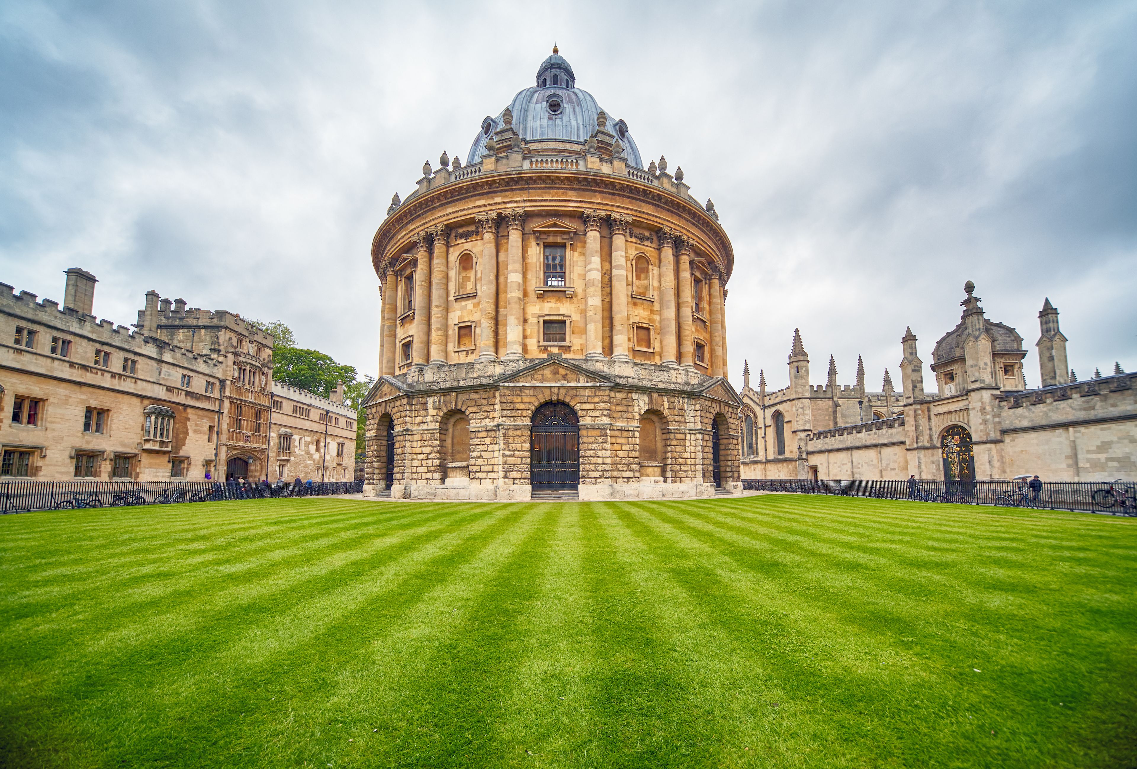 A historic building with a large dome and a circular courtyard with well-manicured grass.