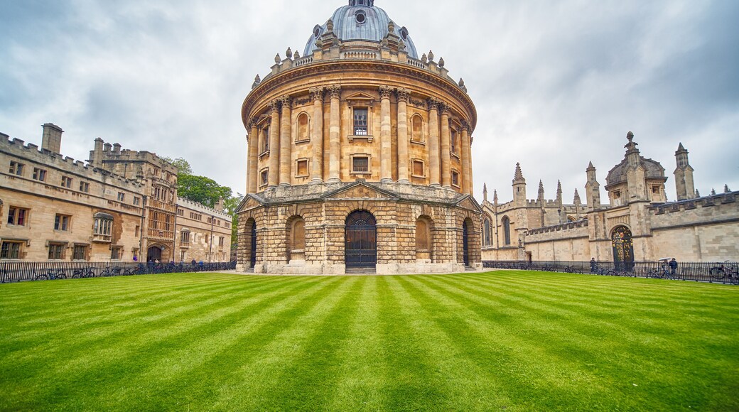 A historic building with a large dome and a circular courtyard with well-manicured grass.