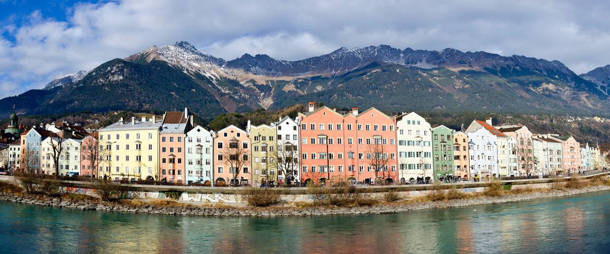 Panorama of river Inn, colourfull house facades and mountain range at Innsbruck
