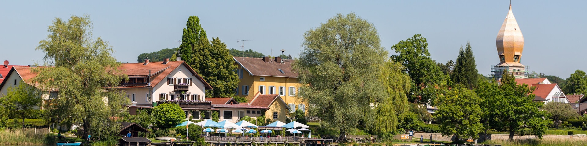 Panorama of Weßling with beer garden, church and lake.