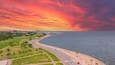 Aerial shot along the coast of Lake Pontchartrain with office buildings and lush green trees and grass at Lakeshore Park in New Orleans Louisiana USA