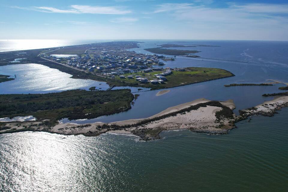 Luchtbeeld van een kustgebied met een jachthaven, woongebouwen en een groot wateroppervlak.
