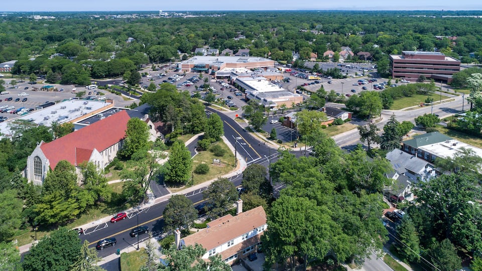 An aerial view of a town with a church, parking lots, and commercial buildings.