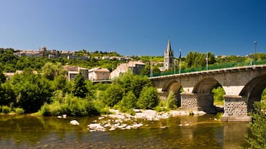 A stone bridge over a river, surrounded by greenery and buildings in the background.