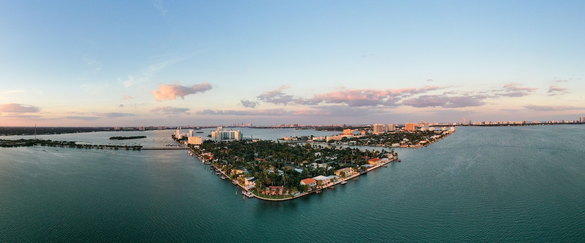 A coastal cityscape with a prominent peninsula featuring residential and commercial buildings, surrounded by water.