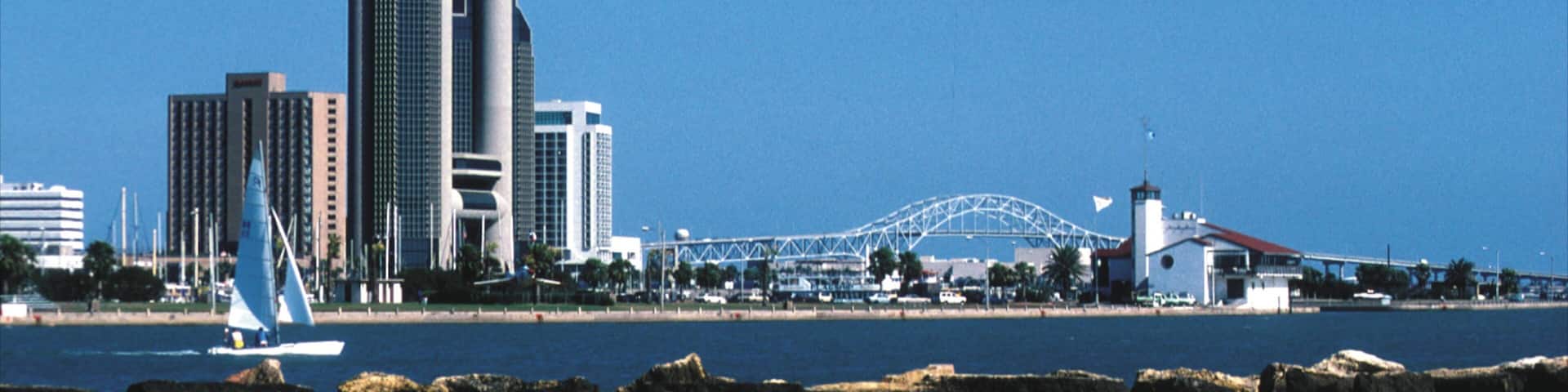 Vibrant waterfront view of Corpus Christi showcasing urban skyline and sailing activity on a clear day