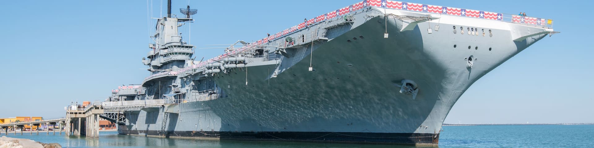 Un grand navire de guerre était amarré à un quai, sous un ciel dégagé.