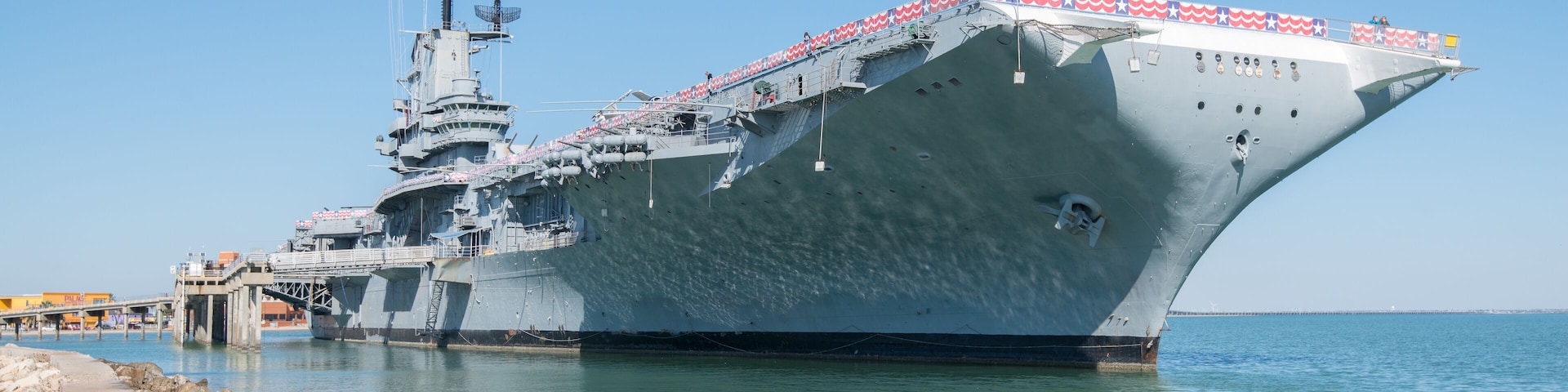 Un grand navire de guerre était amarré à un quai, sous un ciel dégagé.