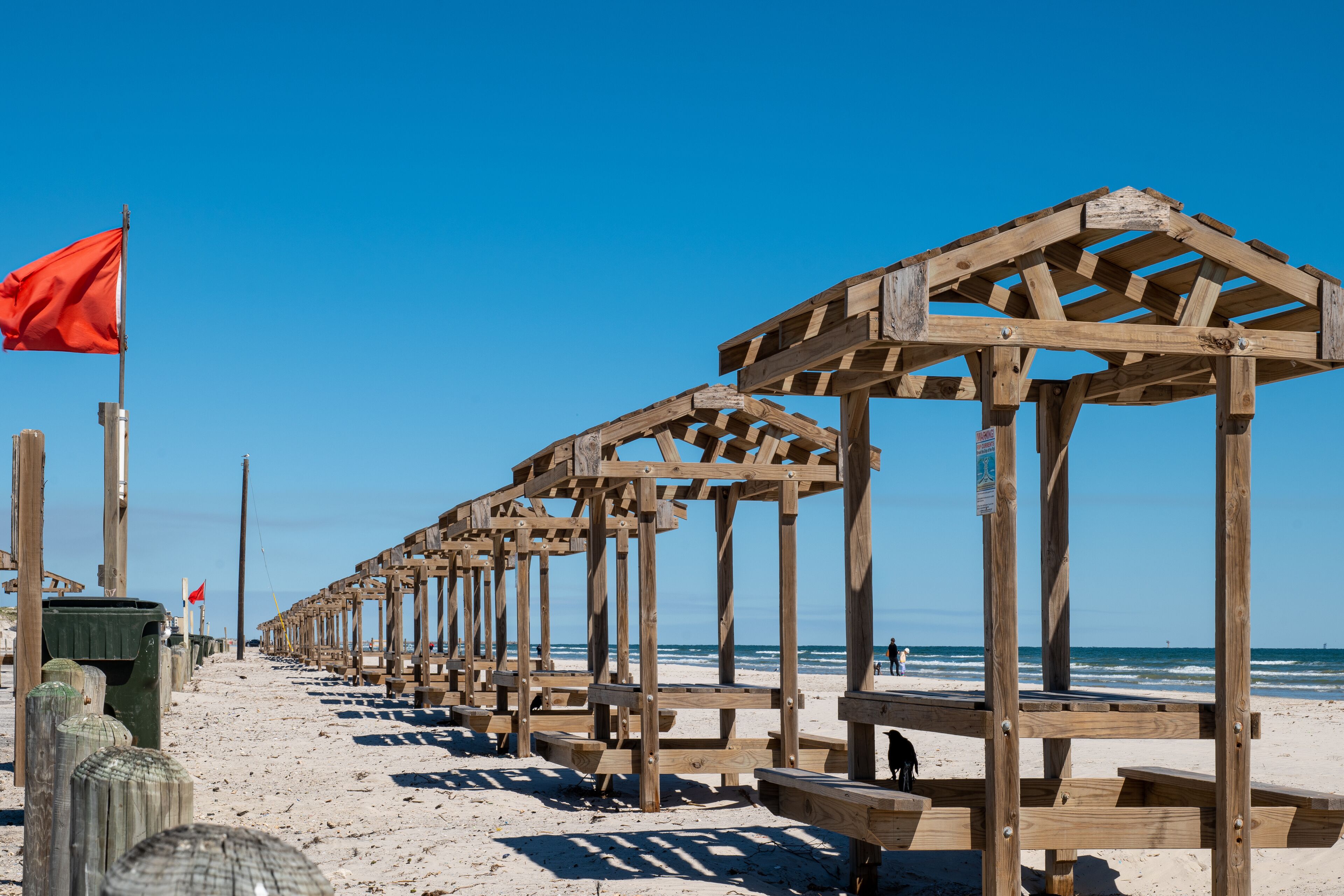Una estructura de madera en la playa con una bandera roja.