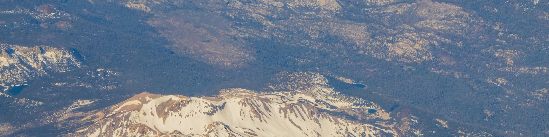 A snow-covered mountain range with visible roads and clearings.