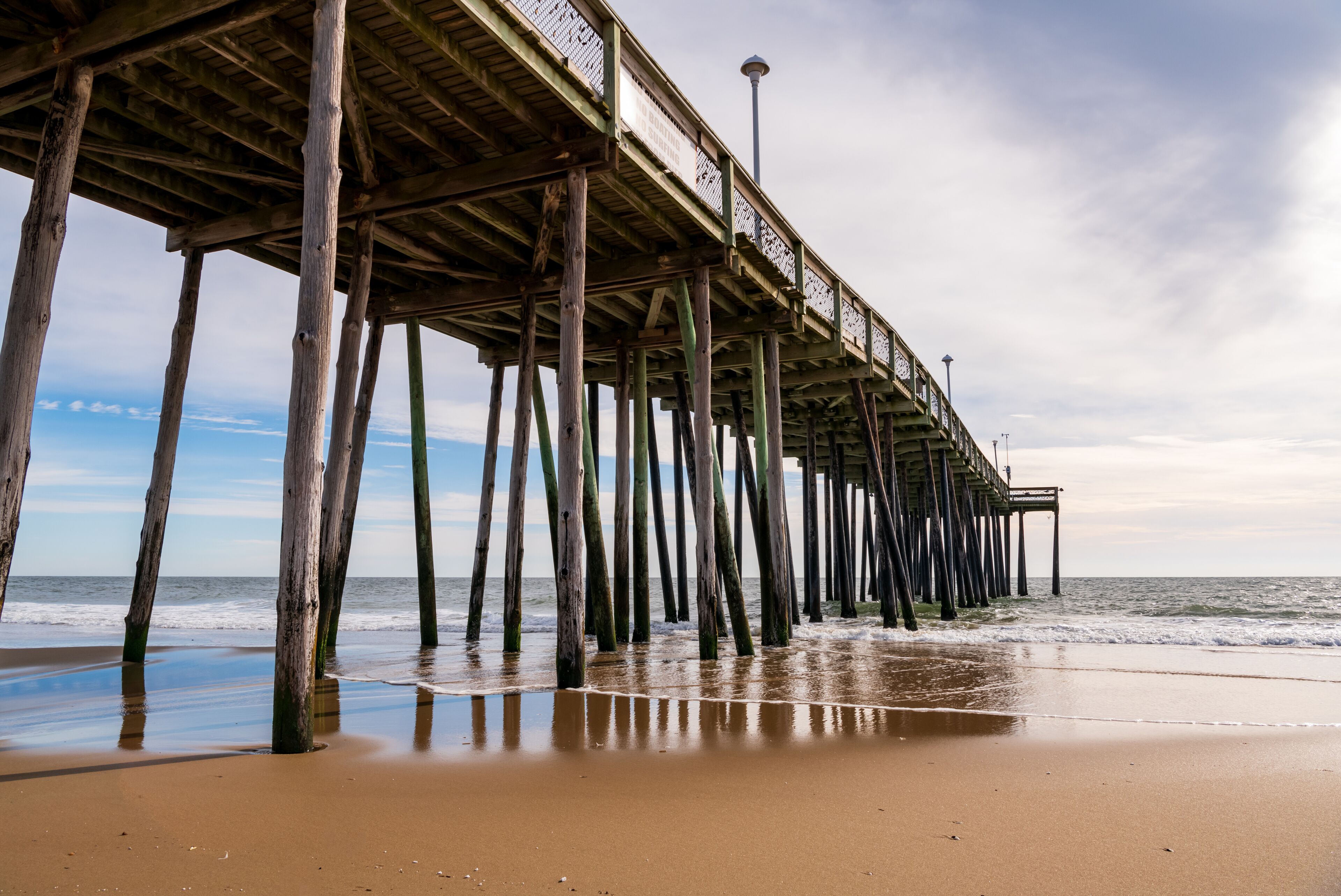 A wooden pier extending into the ocean with a clear sky above.
