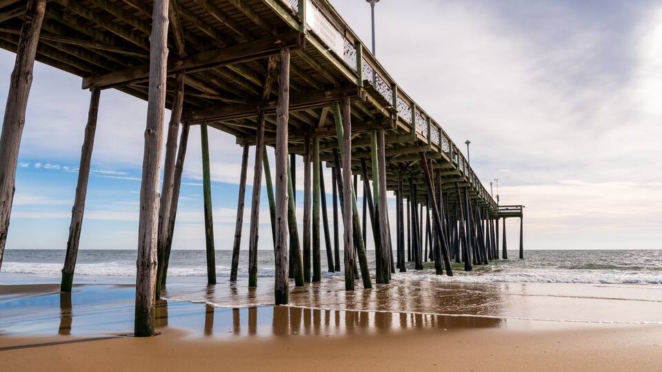 A wooden pier extending into the ocean with a clear sky above.