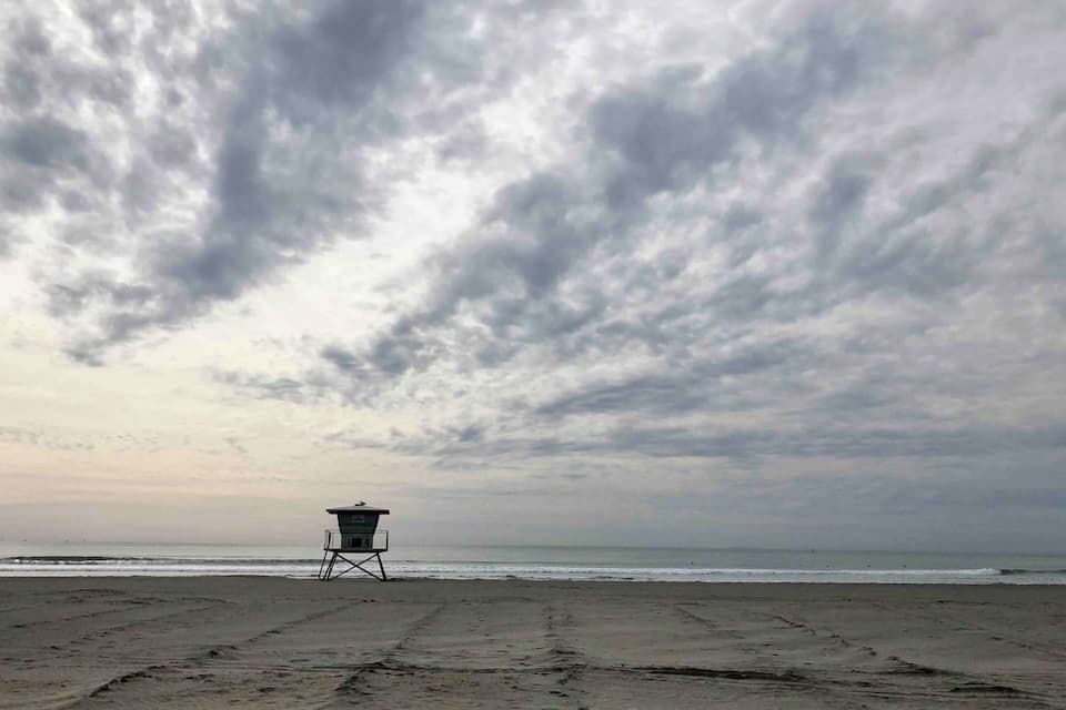 A lifeguard tower on a beach with a cloudy sky.