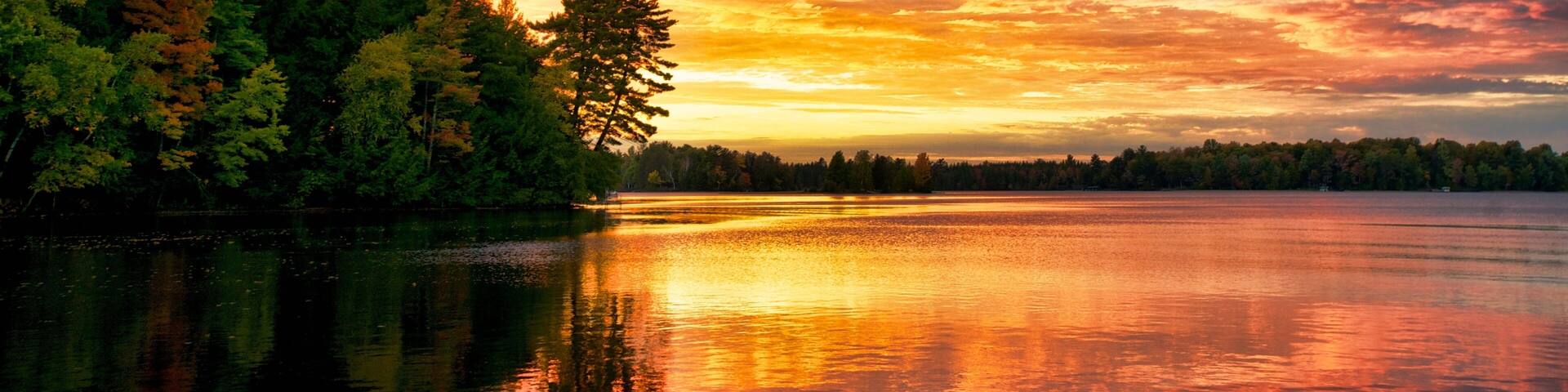 A sunset over a lake with a forested shoreline.