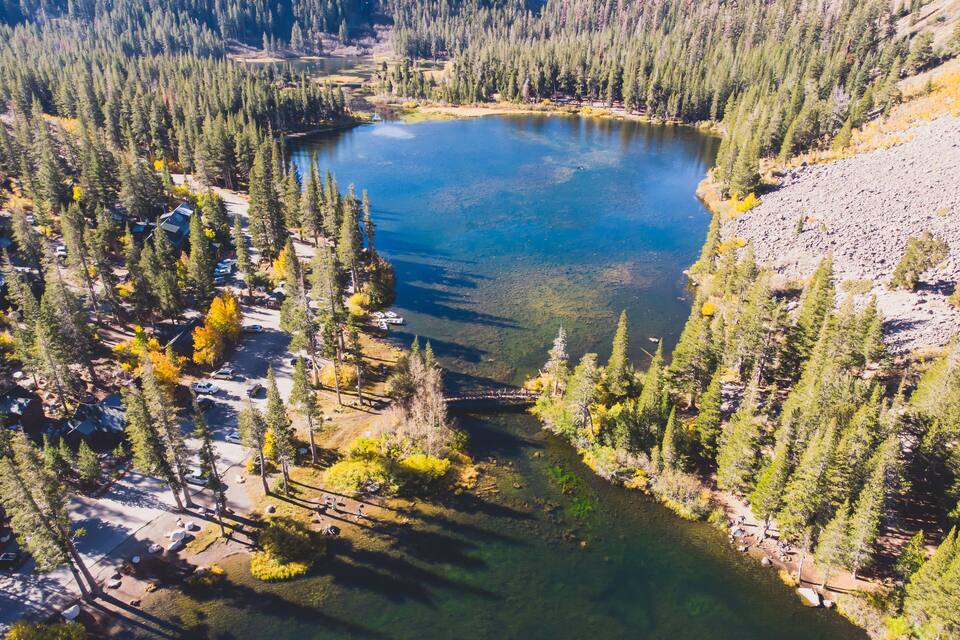 A clear lake surrounded by dense forest and a campground with cabins.