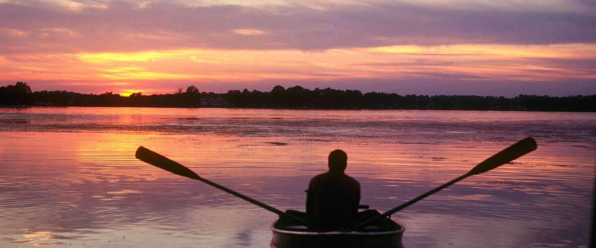 Silhouette of man peacefully rowing boat at sunset. Lake Kegonsa Wisconsin WI USA