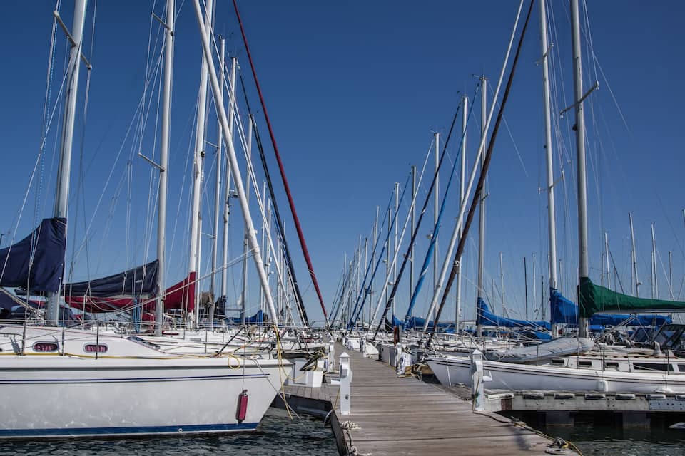 Un puerto deportivo con varios veleros amarrados a un muelle de madera.