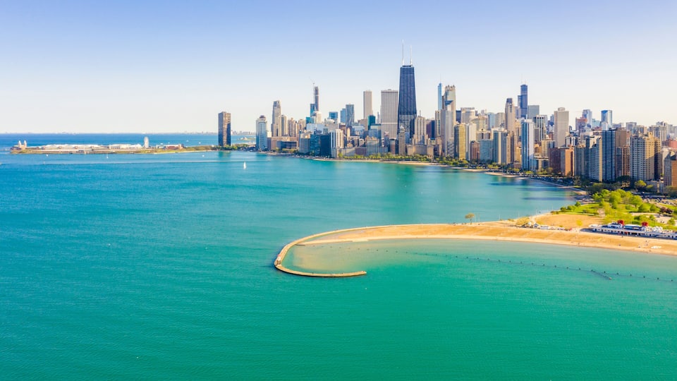 A coastal cityscape with a prominent skyscraper, a curved bay, and a distant shoreline.