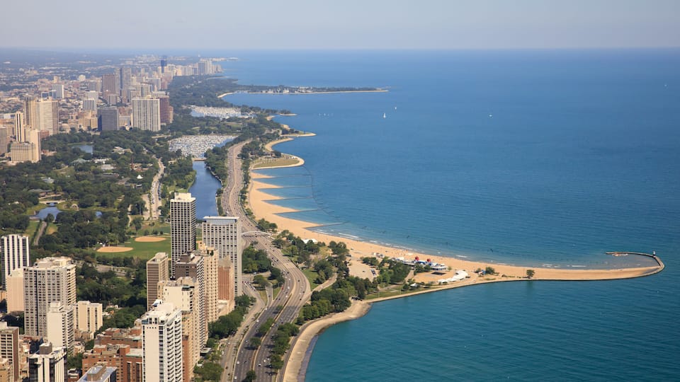 A coastal city with a beach, high-rise buildings, and a curved road along the shore.