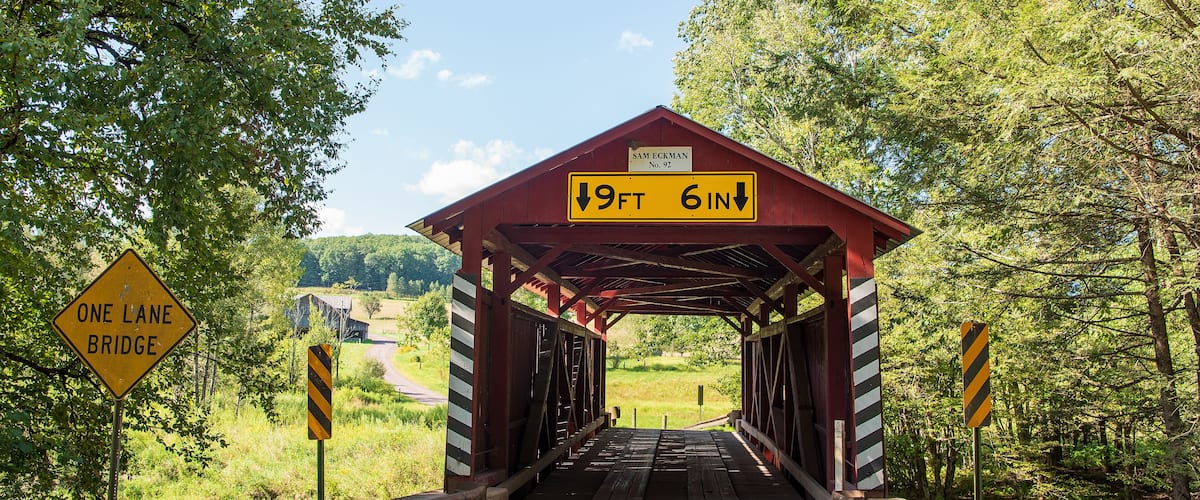 A wooden covered bridge with a height restriction sign of 9ft 6in.