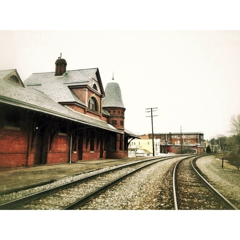 A railway station with a brick building, a dome, and tracks curving to the right.