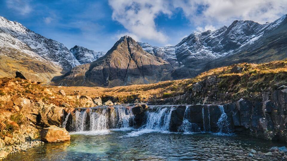 A mountainous landscape with a waterfall and a prominent peak.