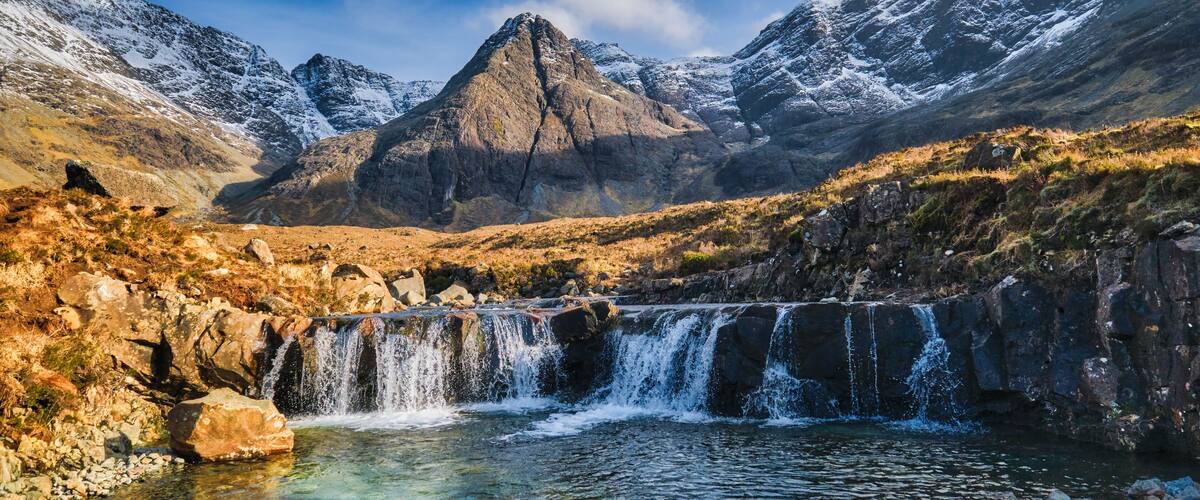 A mountainous landscape with a waterfall and a prominent peak.