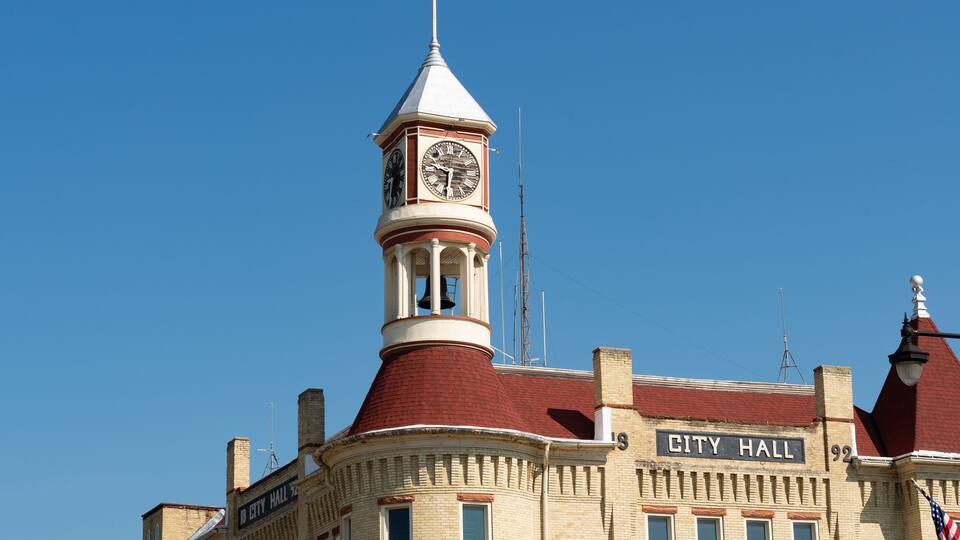 A historic building with a clock tower and a sign that reads "City Hall."