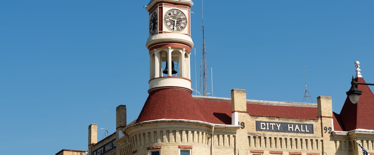 A historic building with a clock tower and a sign that reads "City Hall."