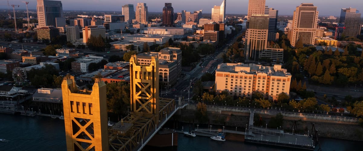 A cityscape with a prominent bridge, high-rise buildings, and a river.