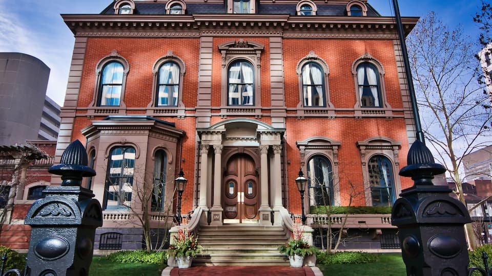 A large red brick building with a grand entrance, large windows, and decorative columns.