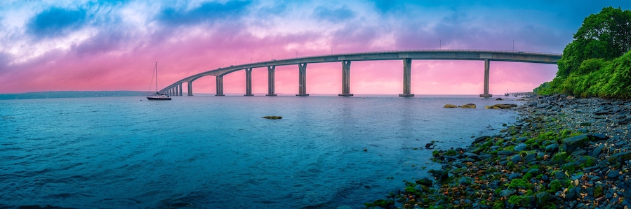 Un puente sobre el agua, con un bote y una orilla rocosa.
