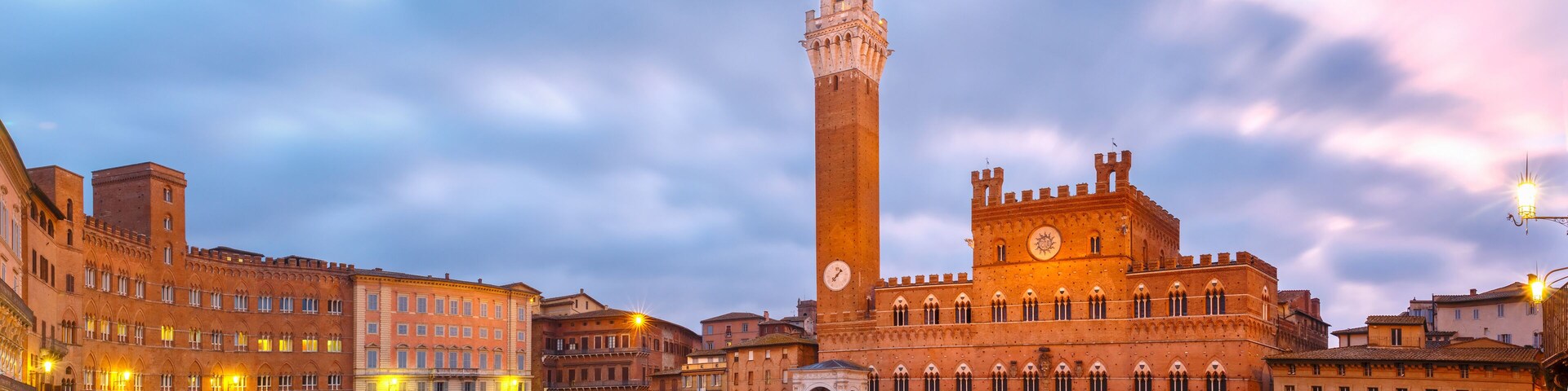 Mangia Tower or Torre del Mangia towering above of the Palazzo Pubblico on Piazza del Campo in medieval city of Siena at beautiful sunrise, Tuscany, Italy