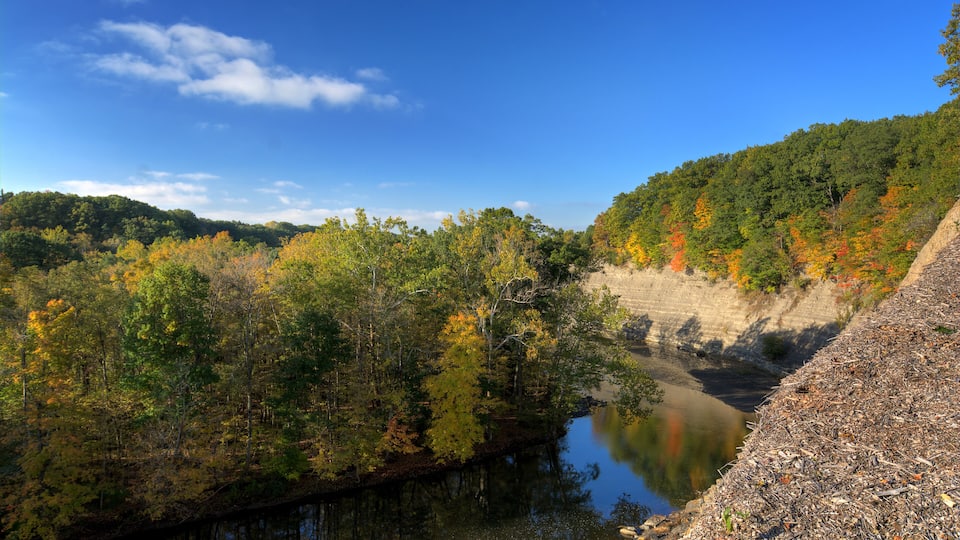 A river surrounded by autumn foliage, a steep cliff, and a clear blue sky.