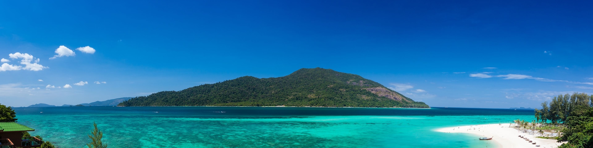 Uma ilha tropical com águas turquesa cristalinas, uma praia de areia branca e colinas verdejantes.