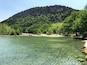 A clear lake surrounded by lush green trees and a rocky mountain.