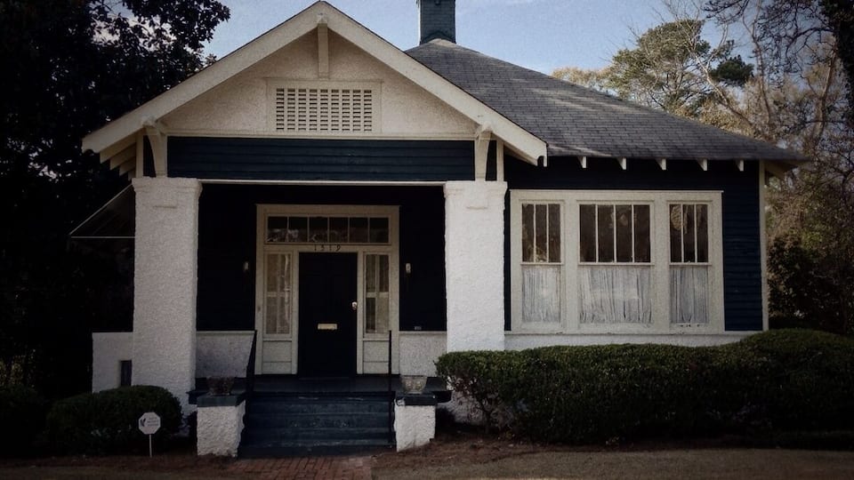 The family of author Carson McCullers moved to this house in 1927. Here Lula Carson Smith spent her formative years 10-17 and here she began to write, putting on shows in the two sitting rooms, using the sliding doors as curtains and drafting brother Lamar and sister Rita as actors. Shows grew into plays, stories and novels. She left to study writing in New York in 1934. When a teacher told her that the best stories can be found in one's own back yard, her "green arcade" of trees drew her home again. In the summer of 1935 she met James Reeves McCullers, Jr., whom she married in the garden here in Sept., 1937. They moved to North Carolina where the young author completed her first novel The Heart is a Lonely Hunter. During World War II, with Reeves overseas, Carson lived in New York but often returned home to work and rest. She liked to sit in the kitchen, absorbing its warmth, the aroma of food cooking and the conversation of the cook. In her front bedroom she kept her piano and the typewriter where she worked on her novel, and later prize winning-play, The Member of the Wedding. After the death of her father in 1944, Carson and her mother made their home in Nyack, N.Y.