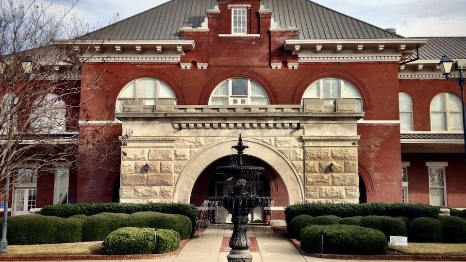 The Central of Georgia Railroad's Station, designed by Bruce and Morgan of Atlanta, GA, was erected in 1901. Featuring massive granite arches, it served as the transportation hub of the city for over 70 years. Threatened with demolition in 1984, this landmark, on the eastern perimeter of the Original City, was saved through the leadership of the Historic Columbus Foundation and the generosity of the Southern Railway System and the Consolidated Government of Columbus and its citizens. The property was listed on the National Register of Historic Places in 1980.