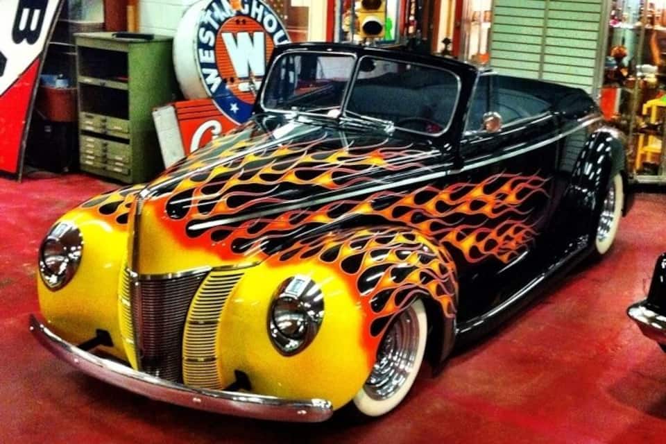 A custom car with flame designs in a garage.