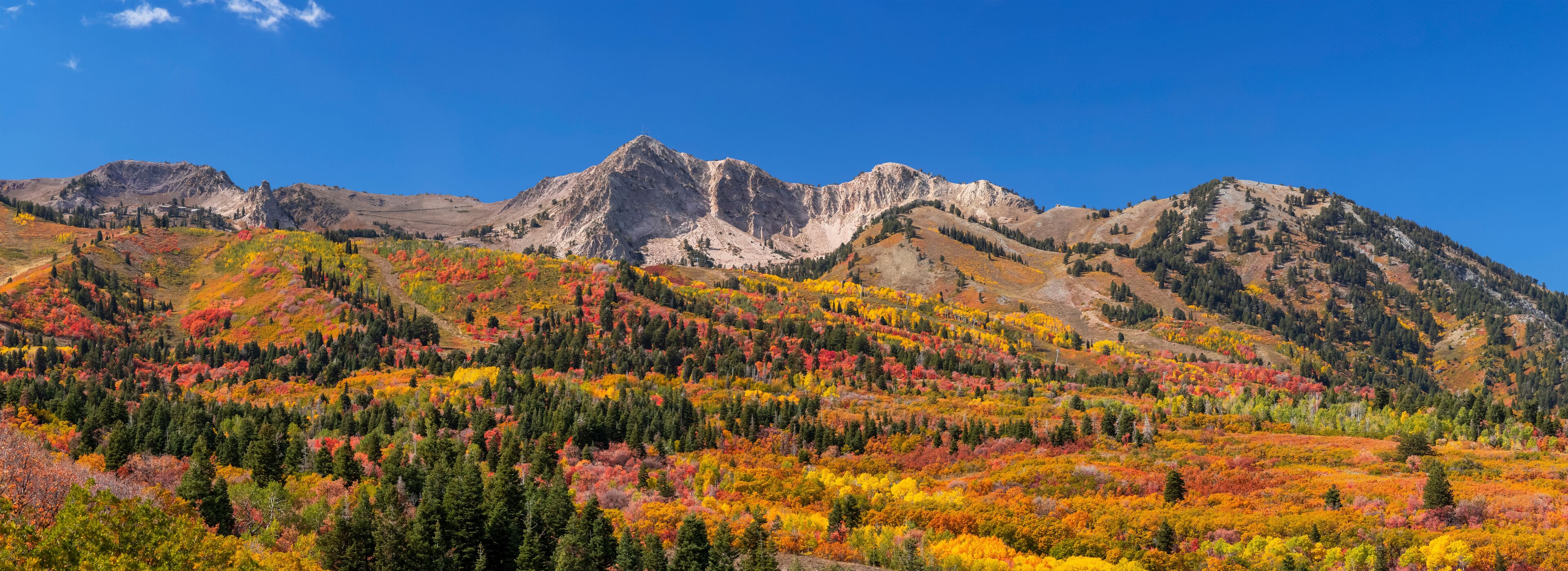 A mountain range with autumn foliage and clear blue skies.