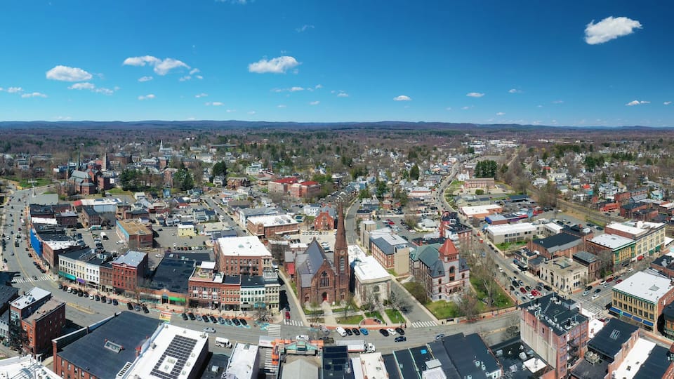 A panoramic view of a town with a mix of historic and modern buildings, a prominent church, and a clear blue sky.
